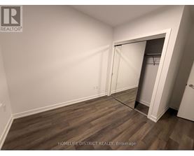 A room with a wooden floor and a white wall with a doorway leading to another room.