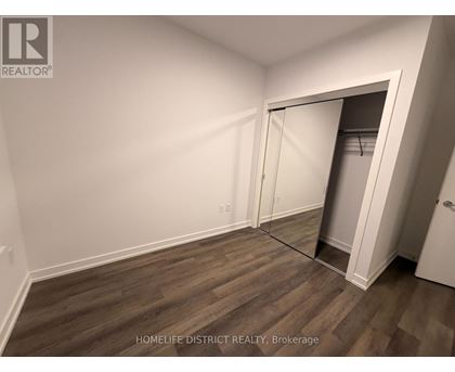 A room with a wooden floor and a white wall with a doorway leading to another room.