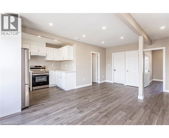 A spacious kitchen with white cabinets and a wood floor.