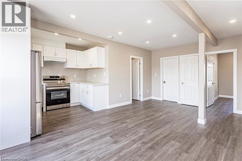 A spacious kitchen with white cabinets and a wood floor.