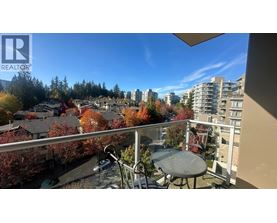 A balcony with a table and chairs overlooks a residential area.