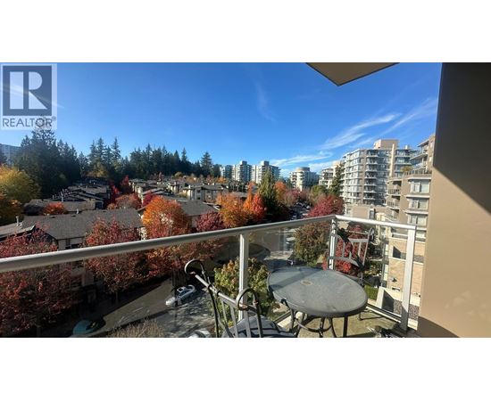 A balcony with a table and chairs overlooks a residential area.
