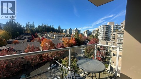 A balcony with a table and chairs overlooks a residential area.