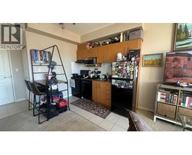 A kitchen with a refrigerator covered in magnets and a chair with a backpack on it.