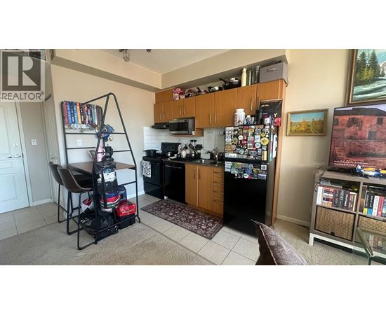 A kitchen with a refrigerator covered in magnets and a chair with a backpack on it.