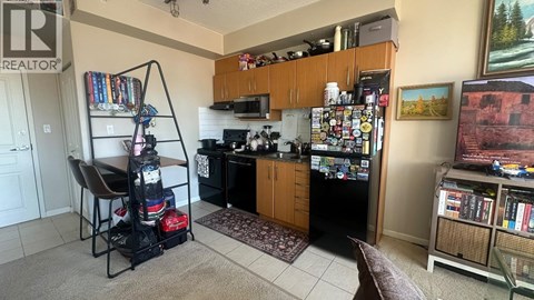 A kitchen with a refrigerator covered in magnets and a chair with a backpack on it.