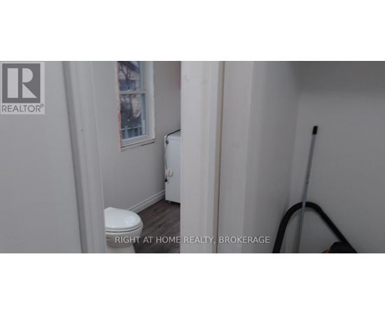 A white toilet in a small bathroom with a REALTOR® logo on the wall.