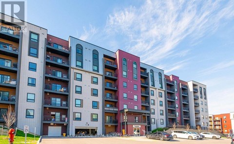 A row of modern apartment buildings with balconies and cars parked in front.