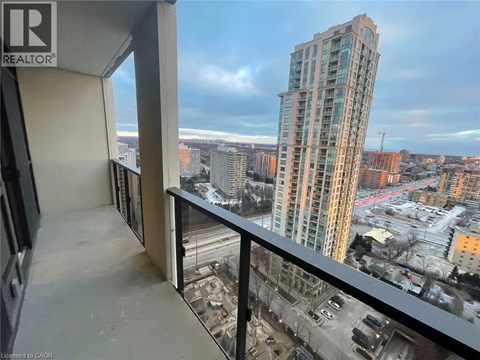 A view from a balcony looking out at a cityscape with a tall building in the distance.