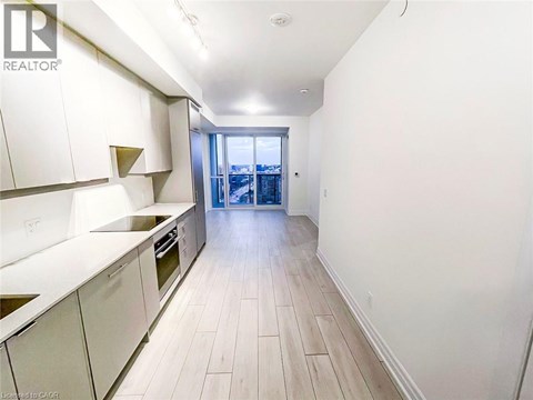 A kitchen with white cabinets and a view of a cityscape through a glass door.