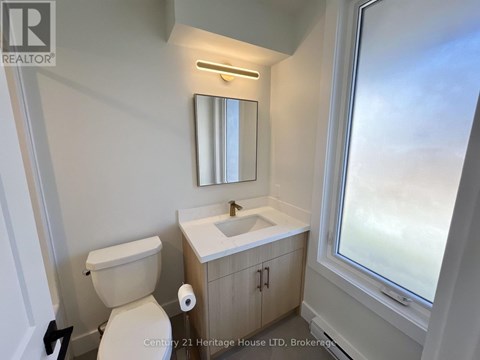 A bathroom with a toilet, sink, and mirror.