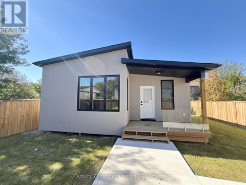 A modern house with a white exterior and a black roof is for sale.