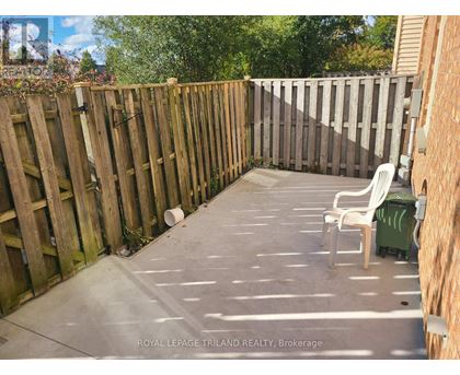 A backyard with a wooden fence and a white chair.