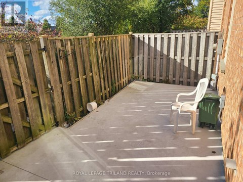 A backyard with a wooden fence and a white chair.