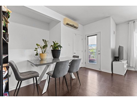 A dining area with a glass table and grey chairs.