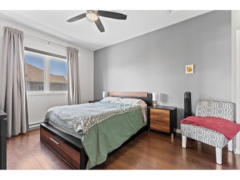 A bedroom with a bed, chair, and window.