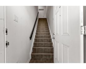 A staircase with a black handrail and white walls.