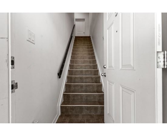 A staircase with a black handrail and white walls.