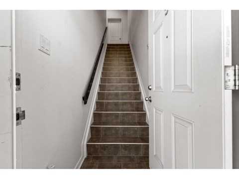 A staircase with a black handrail and white walls.