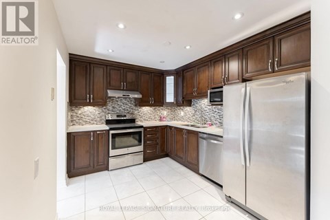 A kitchen with brown cabinets and a stainless steel refrigerator.