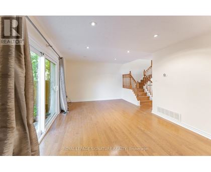 A spacious room with wooden floors and a curved staircase.