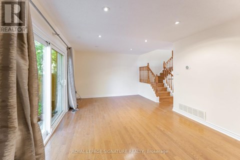 A spacious room with wooden floors and a curved staircase.