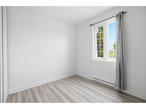 A room with a window and a grey curtain.