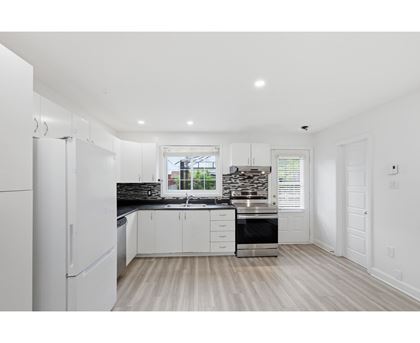 A kitchen with white cabinets and a black countertop.