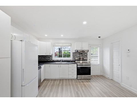A kitchen with white cabinets and a black countertop.