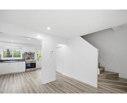 A white interior space with a staircase leading to a second floor.