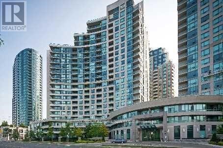 A building with a glass facade is surrounded by other buildings.