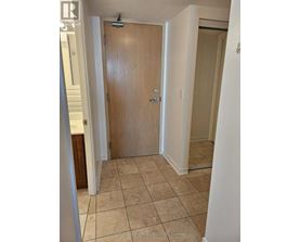 A wooden door is in a room with tiled flooring.