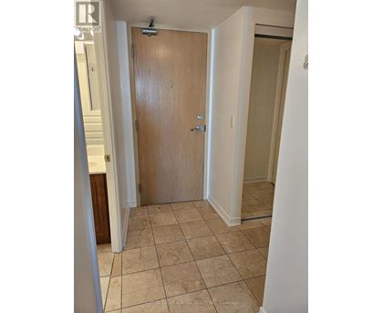 A wooden door is in a room with tiled flooring.