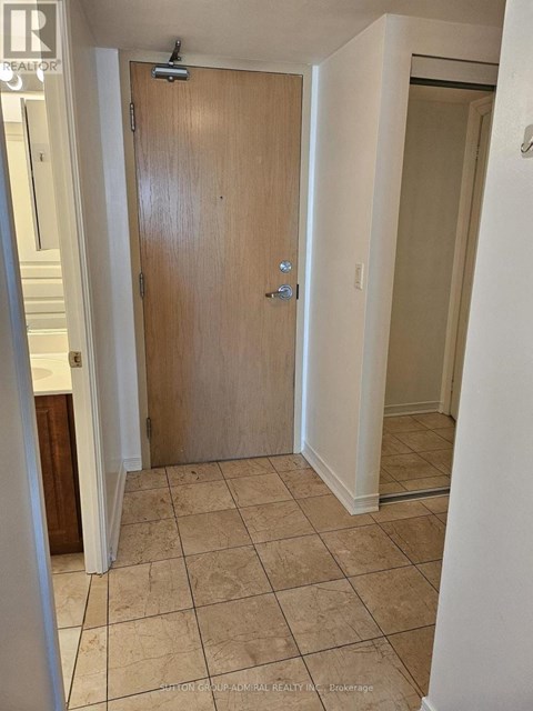 A wooden door is in a room with tiled flooring.