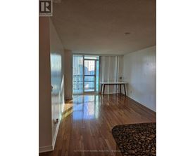 A room with wooden floors and a large window with blinds.