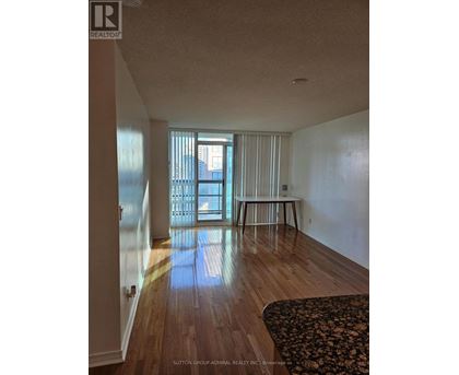 A room with wooden floors and a large window with blinds.