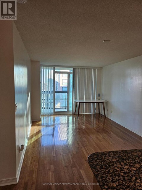 A room with wooden floors and a large window with blinds.