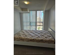 A bedroom with a large window and a bed with a floral patterned bedspread.
