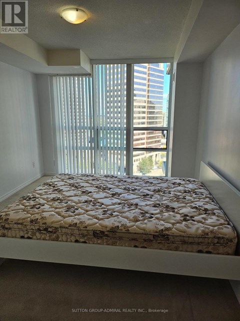 A bedroom with a large window and a bed with a floral patterned bedspread.