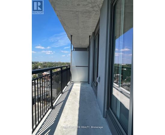 A balcony with a black railing and a view of the city.