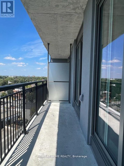 A balcony with a black railing and a view of the city.