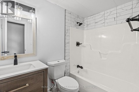 A white bathroom with a toilet, sink, and bathtub.