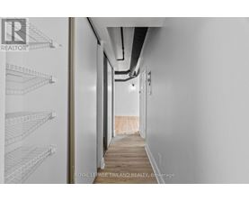 A long hallway with white walls and a wooden floor.