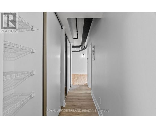 A long hallway with white walls and a wooden floor.