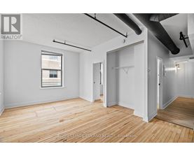 A room with wooden floors and white walls, with a window on the left side.