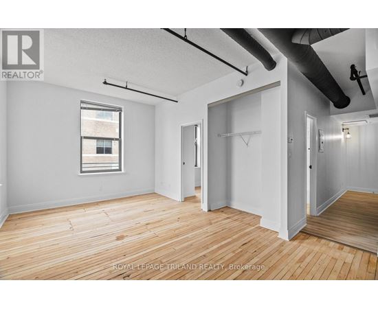 A room with wooden floors and white walls, with a window on the left side.