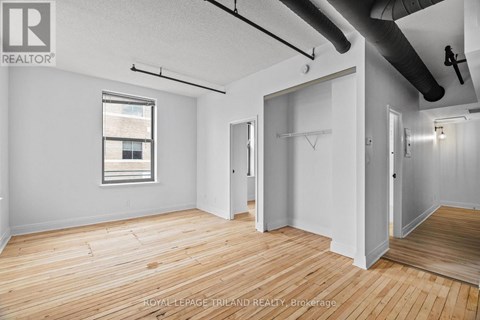 A room with wooden floors and white walls, with a window on the left side.