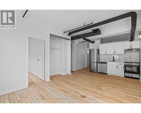 A kitchen with white cabinets and a wooden floor.