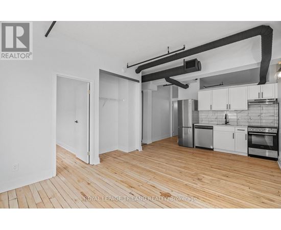 A kitchen with white cabinets and a wooden floor.