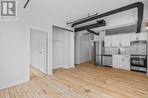 A kitchen with white cabinets and a wooden floor.
